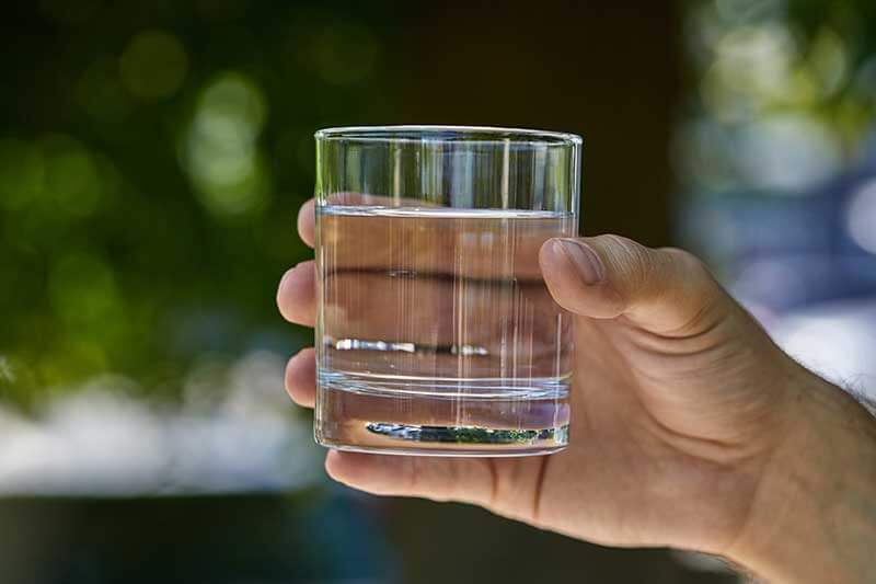 A hand holding a glass of clean drinking water